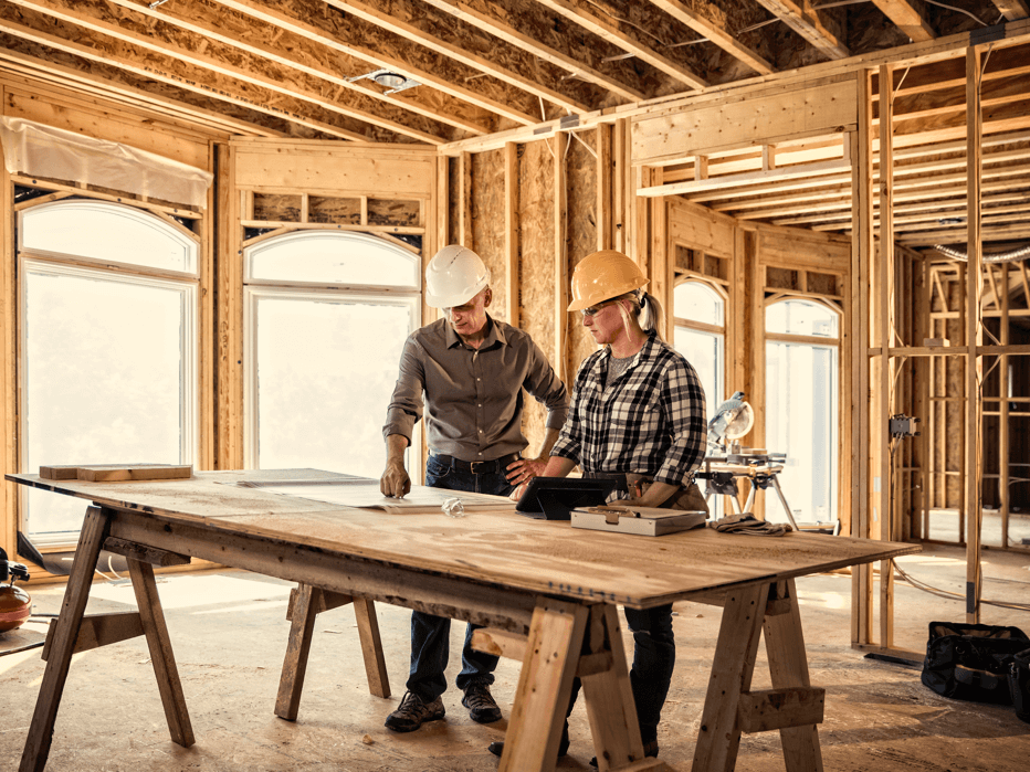 Construction workers discuss over a blueprint.