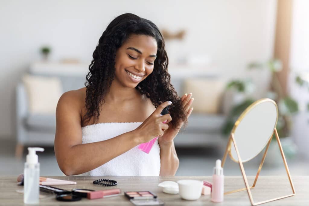Young woman with curly hair applying hair spray.