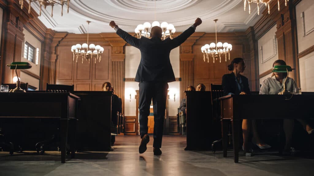 Lawyer walking out of the courtroom with his arms held high.