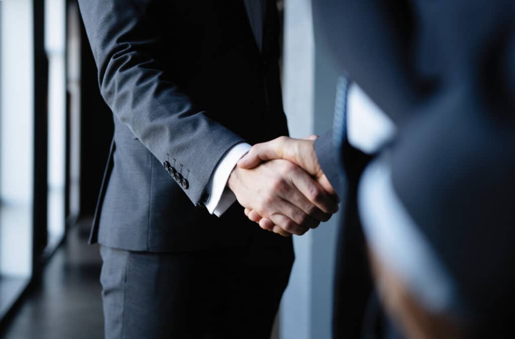 Two men in suits shaking hands.