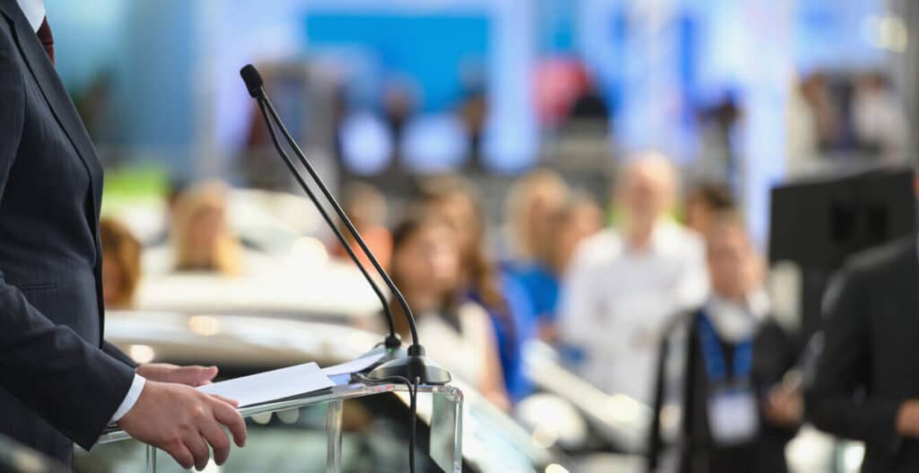 A man at a podium speaking to a crowd of people