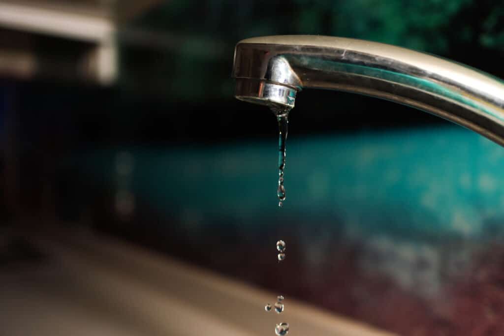 Water slowly dripping from a faucet.