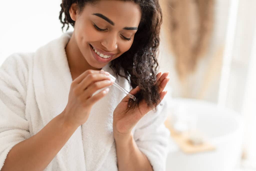 Young woman applying a product to her hair.